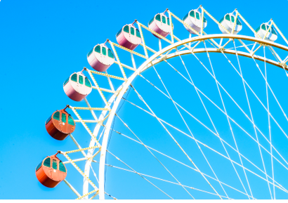 A big wheel against a bright blue sky at a country fair
